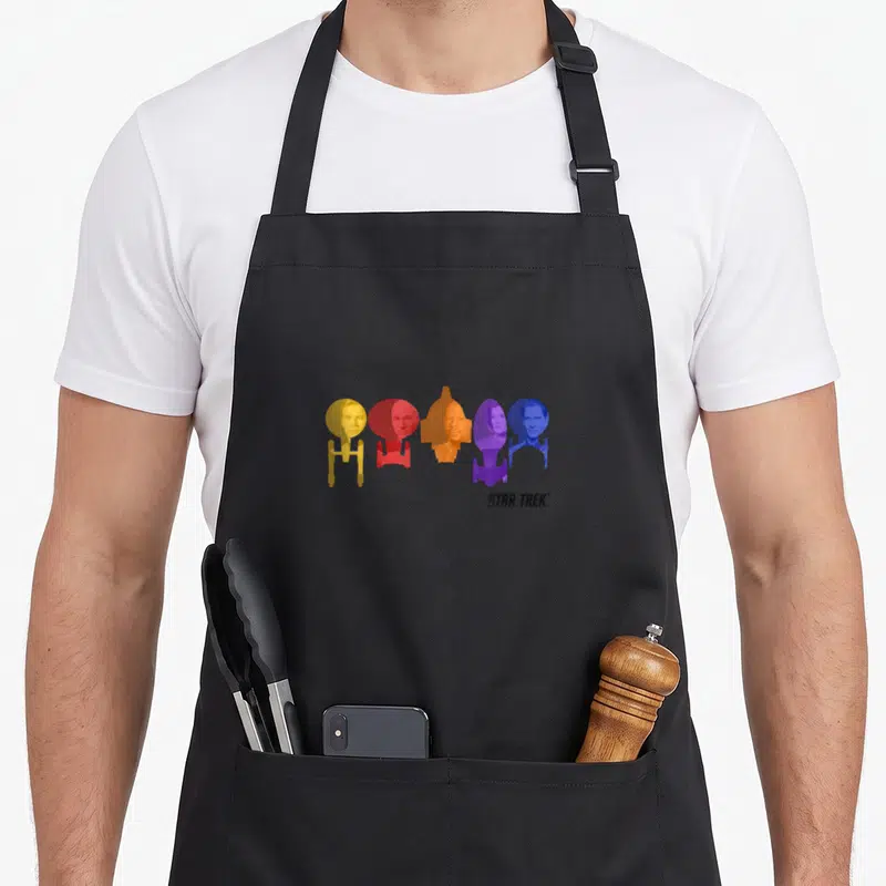 Tablier de cuisine noir avec cinq capitaines de vaisseaux spatiaux aux couleurs vives alignés horizontalement.