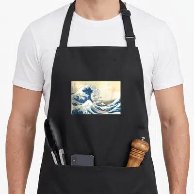 Tablier de cuisine noir avec Snoopy surfeur sur une reproduction de La Grande Vague de Hokusai en bleu et beige.