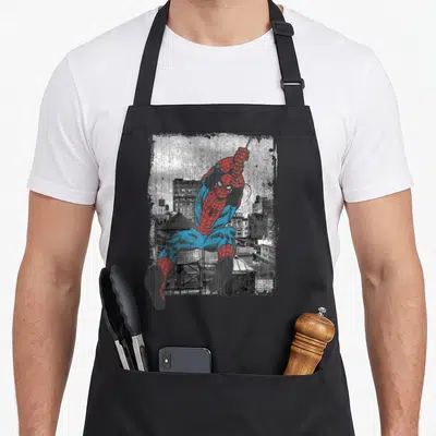 Tablier de cuisine noir avec une illustration vintage de Spider-Man en tenue rouge et bleue se balançant au-dessus d'une ville en gris.