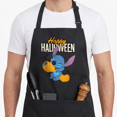 Tablier de cuisine noir avec Stitch tenant une citrouille orange sous le texte Happy Halloween et des chauves-souris noires.