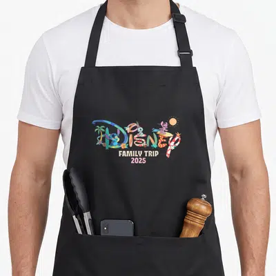 Tablier de cuisine noir avec motif Disney Family Trip 2025 Vacation coloré sur fond uni.