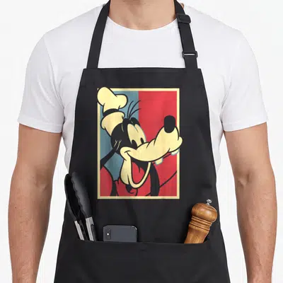 Tablier de cuisine noir avec une illustration de Goofy en style pop art aux couleurs rouge et bleu sur fond géométrique.