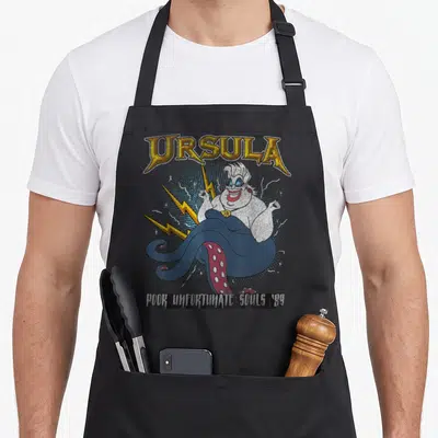 Tablier de cuisine noir avec portrait vintage d'Ursula, éclairs jaunes et texte Poor Unfortunate Souls '89 en bas.