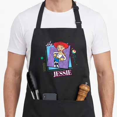 Tablier de cuisine noir avec une illustration colorée de Jessie et le texte His Jessie sur fond géométrique.