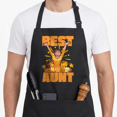 Tablier de cuisine noir avec illustration de Pepa Best Aunt entourée de fleurs jaunes et oranges.