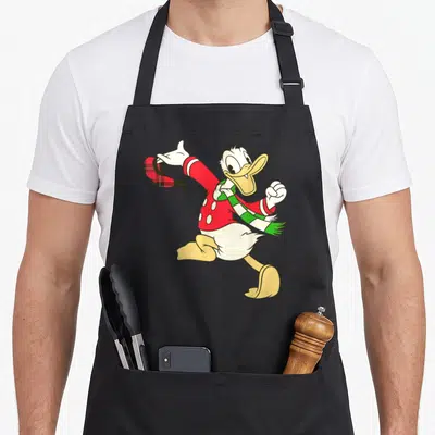 Tablier de cuisine noir avec illustration colorée de Donald Duck portant un foulard vert et tenant un chapeau à carreaux rouges.