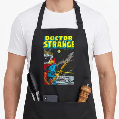 Tablier de cuisine noir avec illustration rétro du Docteur Strange tenant une lance sous un ciel étoilé.