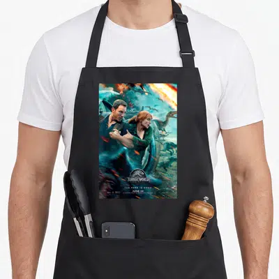 Tablier de cuisine noir avec l'affiche de Jurassic World Two montrant Owen et Claire face aux dinosaures volants.