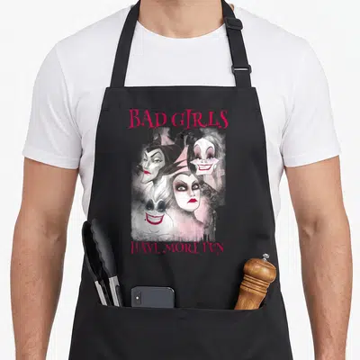 Tablier de cuisine noir avec quatre visages de villaines et le texte Bad Girls Have More Fun en rose.