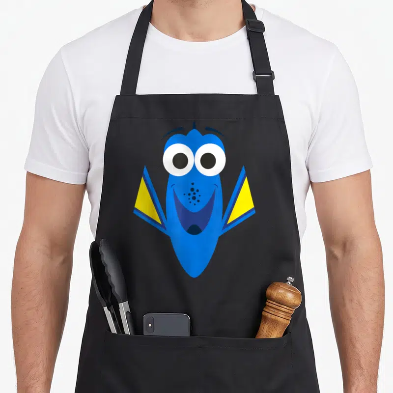Tablier de cuisine noir avec le grand visage souriant de Dory en bleu et jaune.