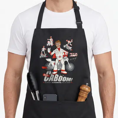 Tablier de cuisine noir avec illustration de Duke Caboom sur moto blanche et texte King of the Jump.