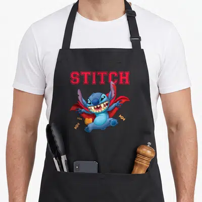 Tablier de cuisine noir avec Stitch en vampire portant une cape rouge et tenant des bonbons colorés.