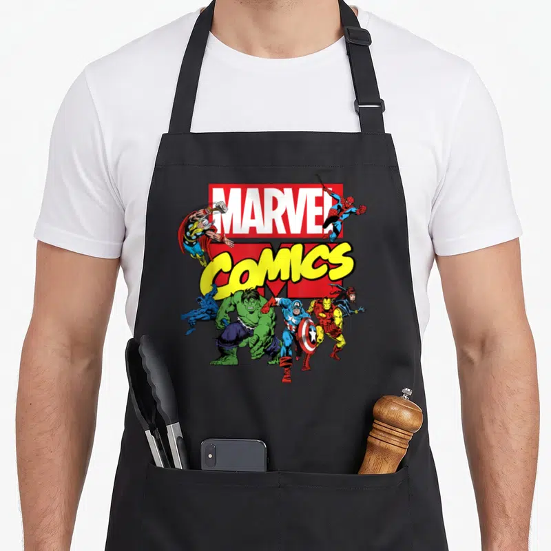 Tablier de cuisine noir avec logo Marvel Comics et illustration rétro des Avengers en action.