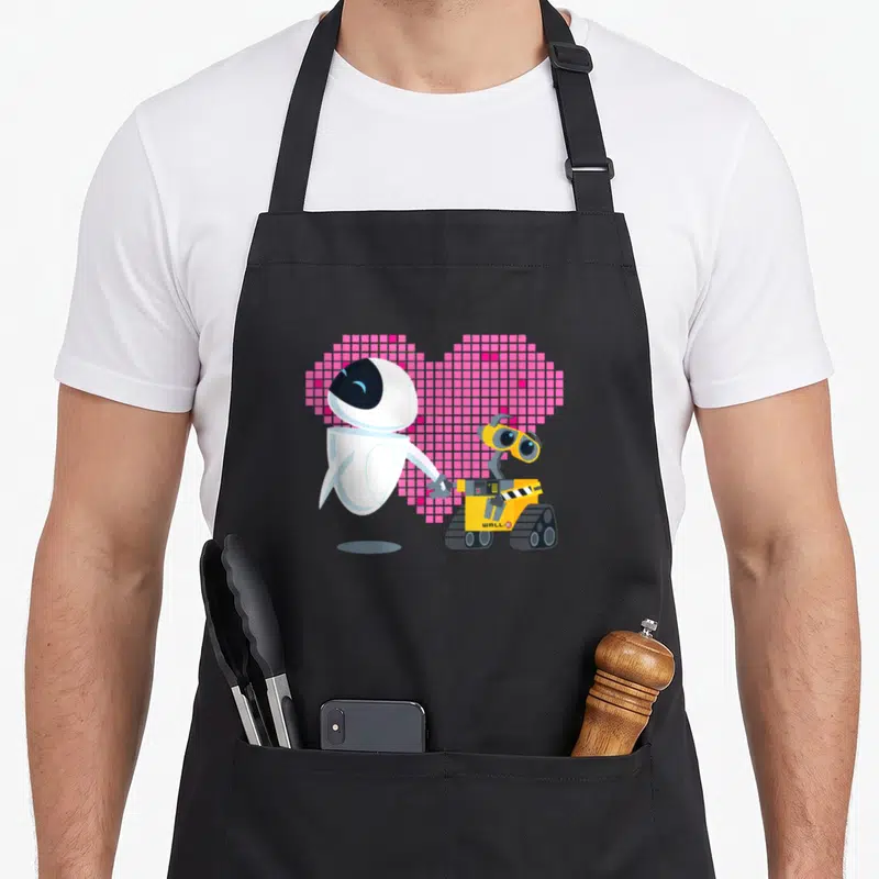 Tablier de cuisine noir avec Wall-E et Eve tenant la main devant un cœur rose pixelisé.