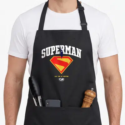 Tablier de cuisine noir avec le logo Superman College et la mention Last Son of Krypton en dessous du bouclier emblématique.