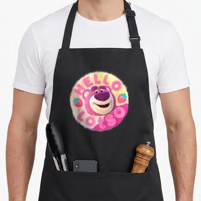 Tablier de cuisine noir avec un ours rose féroce et des fraises dans un motif circulaire.