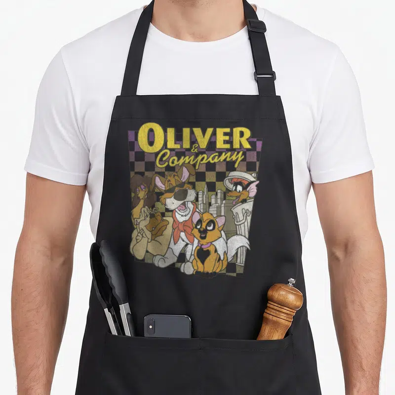 Tablier de cuisine noir avec illustration rétro d'Oliver et ses amis chiens sur fond damier pastel et skyline urbain.