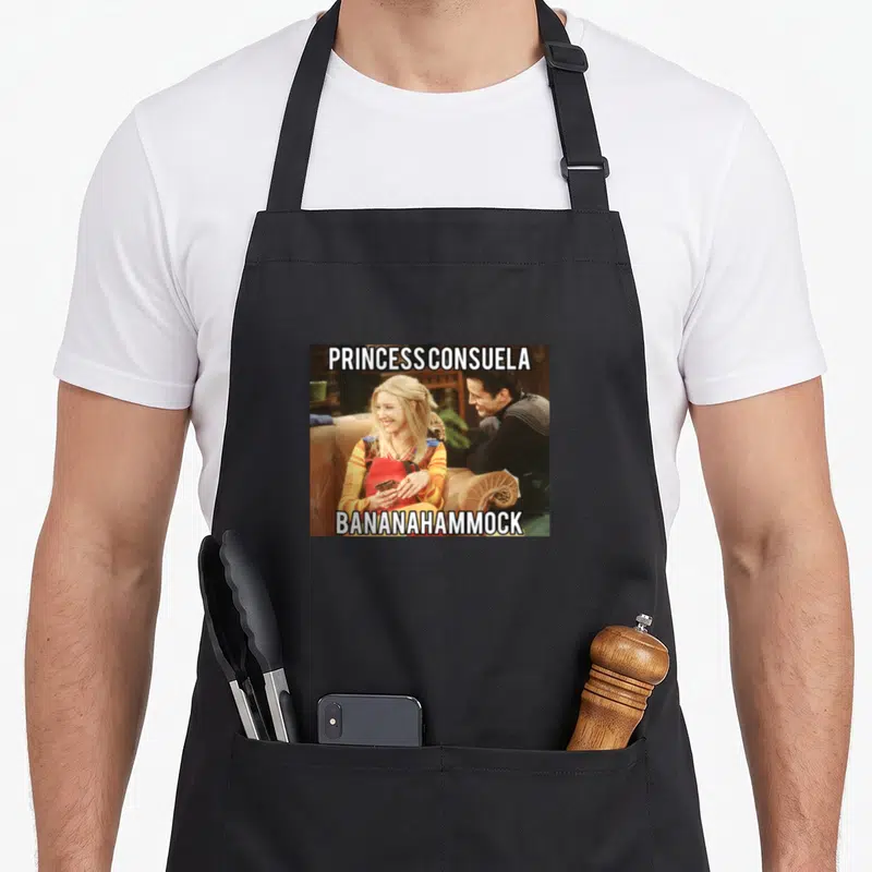 Tablier de cuisine noir avec une illustration de Phoebe Buffay et le texte Princess Consuela Bananahammock imprimé en blanc.