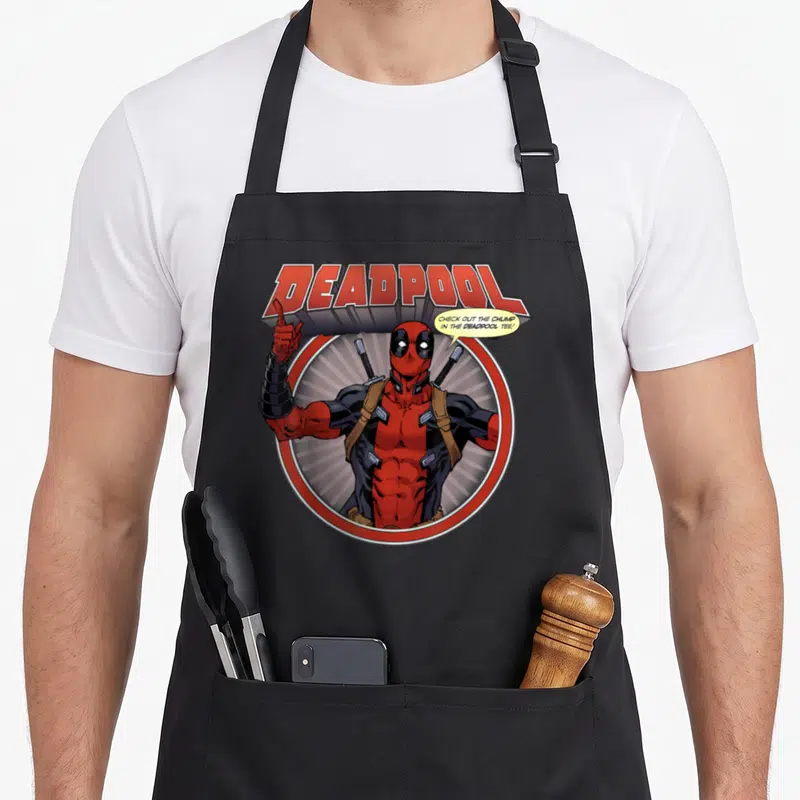 Tablier de cuisine noir avec Deadpool pointant vers le haut et une bulle de dialogue humoristique.