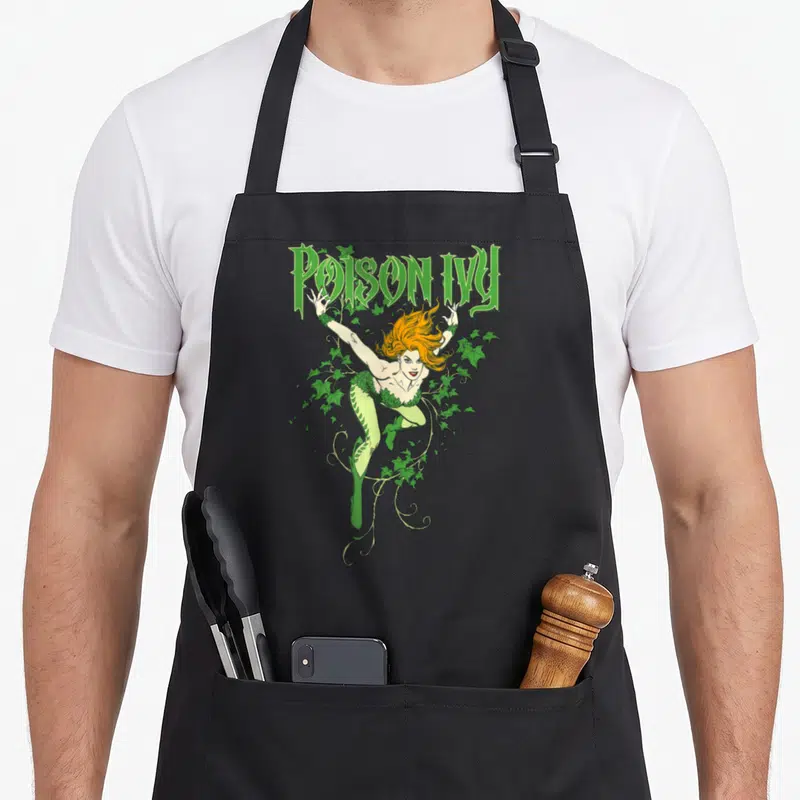 Tablier de cuisine noir avec illustration de Poison Ivy aux cheveux orange entourée de lierre vert et du texte Poison Ivy en haut.