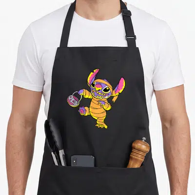 Tablier de cuisine noir avec Stitch momie tenant un pot de bonbons Halloween coloré.