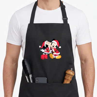 Tablier de cuisine noir avec Mickey et Minnie Santa s'embrassant en tenue de Noël rouge et blanche.
