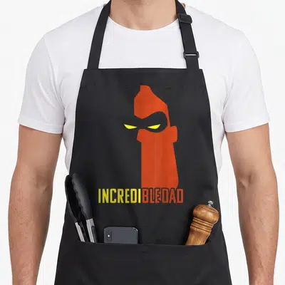 Tablier de cuisine noir avec silhouette orange Incrédibledad aux yeux jaunes et texte stylisé en bas.