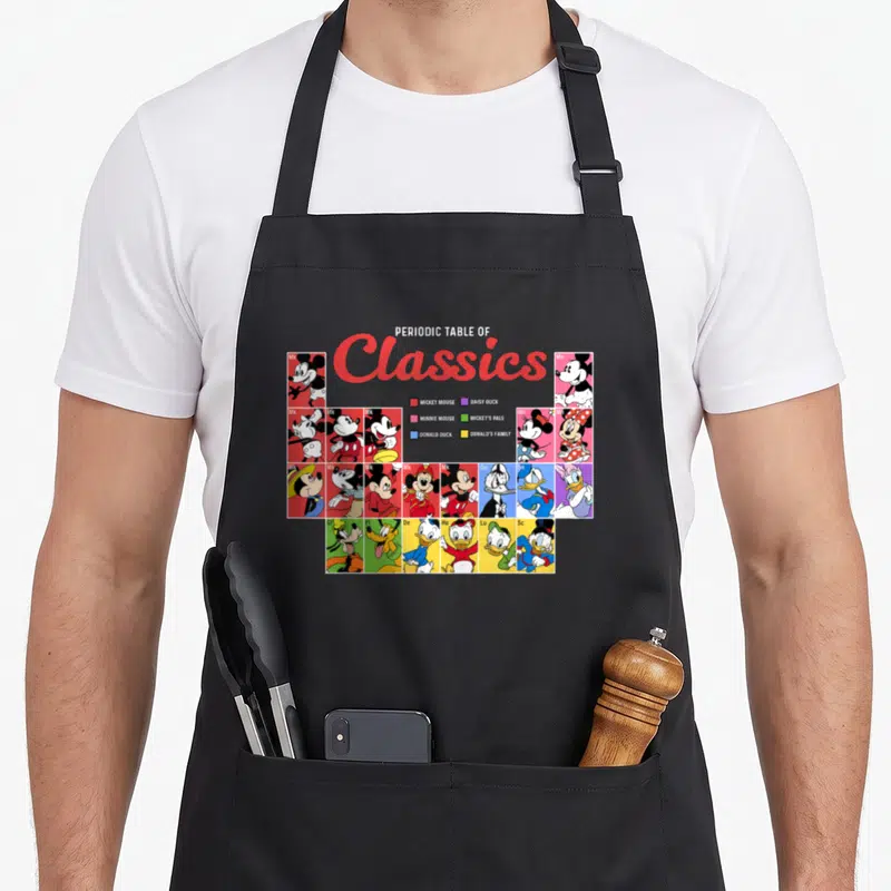 Tablier de cuisine noir avec un tableau périodique coloré illustrant Mickey Mouse et ses amis dans un style scientifique.