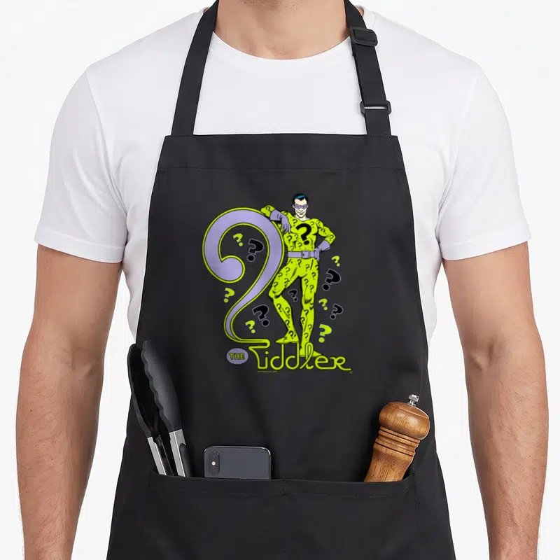 Tablier de cuisine noir avec illustration colorée du Riddleur et grandes questions violettes.
