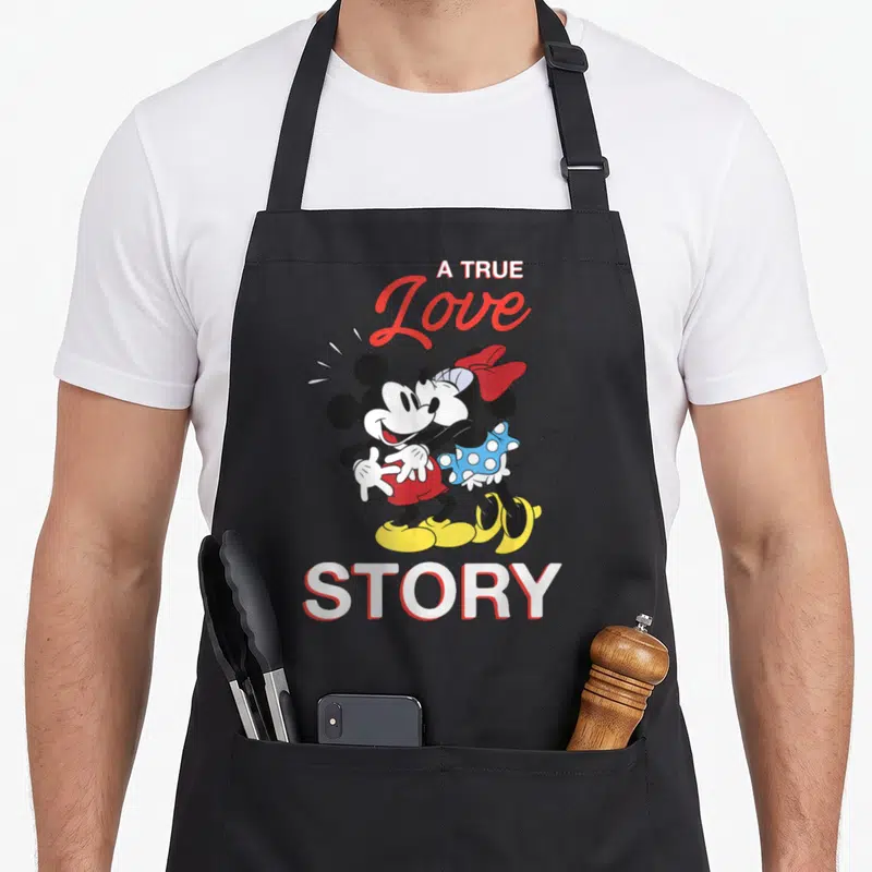 Tablier de cuisine noir avec Mickey et Minnie s'embrassant sous le texte A True Love Story.