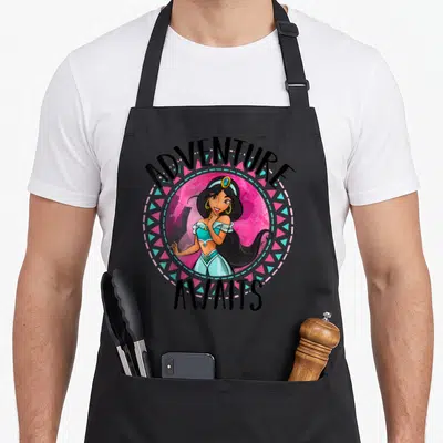 Tablier de cuisine noir avec Jasmine et le texte Adventure Awaits dans un cercle rose et turquoise.