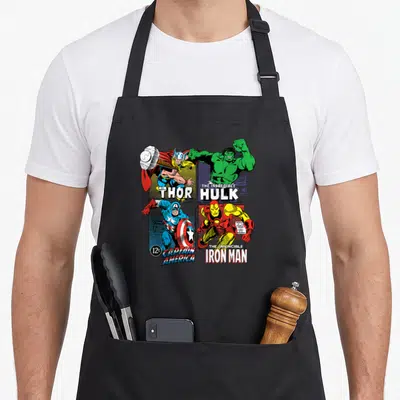 Tablier de cuisine noir avec illustration quadrillée de Thor, Hulk, Captain America et Iron Man au style comics vintage.
