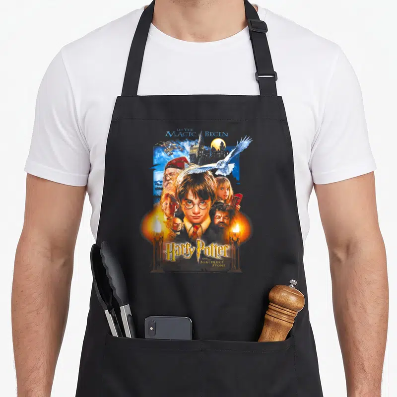 Tablier de cuisine noir avec illustration colorée du poster Harry Potter et une hibou blanche en vol.