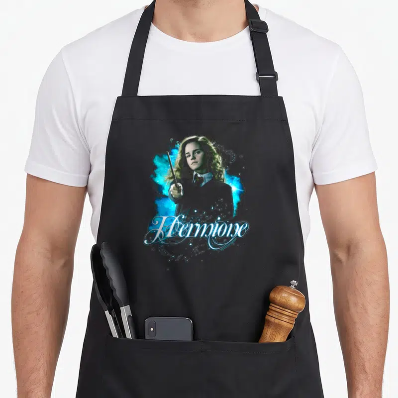 Tablier de cuisine noir avec Hermione brandissant une baguette entourée d'éclats magiques bleus et du mot Hermione en écriture cursive.