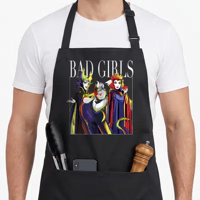 Tablier de cuisine noir avec illustration de trois vilaines princesses et le texte Bad Girls en blanc au-dessus.