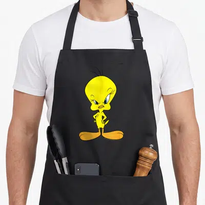 Tablier de cuisine noir avec l'illustration de Tweety aux yeux bleus et plumage jaune vif, posant les mains sur les hanches avec un air mécontent.