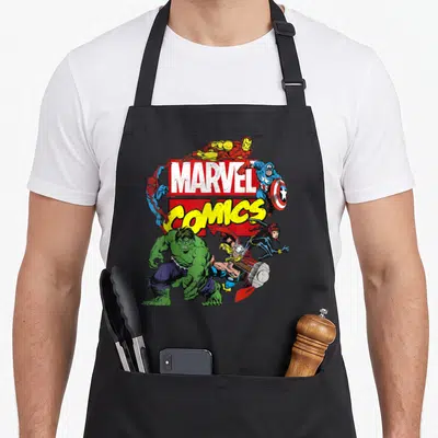 Tablier de cuisine noir avec une illustration colorée regroupant des personnages de comics autour d'un logo rectangulaire rouge et jaune.