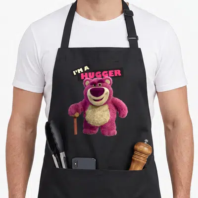 Tablier de cuisine noir avec illustration de l'ours rose Lotso tenant une canne et le texte I'm a Hugger en haut.