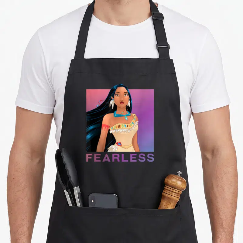Tablier de cuisine noir avec illustration de Pocahontas et le mot FEARLESS en dégradé violet sur fond uni.