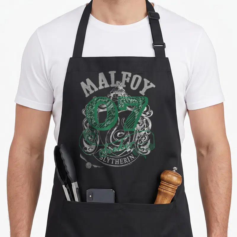 Tablier de cuisine noir avec l inscription Malfoy 07 Seeker Slytherin en vert et gris sur fond d armoiries stylisées