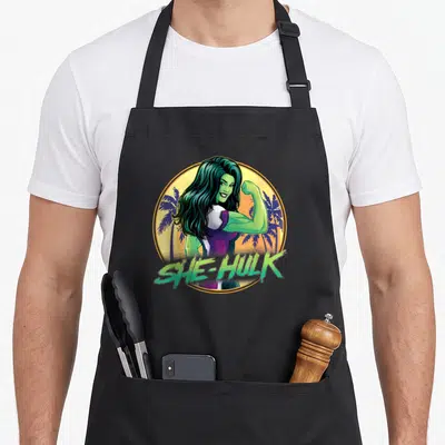 Tablier de cuisine noir avec illustration circulaire de She-Hulk vert fluo et texte She-Hulk en bas.
