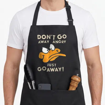 Tablier de cuisine noir avec un dessin de Daffy Duck orange et du texte beige en anglais.