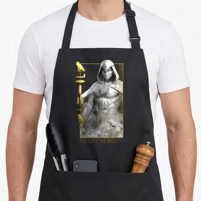Tablier de cuisine noir avec illustration Moon Knight, glyphes dorés, hiéroglyphes et texte Moon Knight en bas.