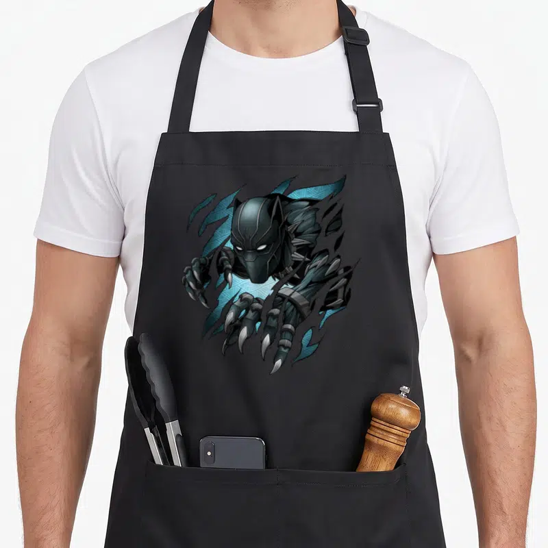 Tablier de cuisine noir avec illustration du Black Panther T'Challa émergeant avec ses griffes acérées et des motifs tribaux bleus.