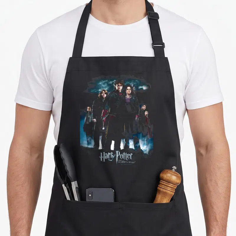 Tablier de cuisine noir avec une illustration groupée de personnages magiques sous un ciel nocturne bleuté.