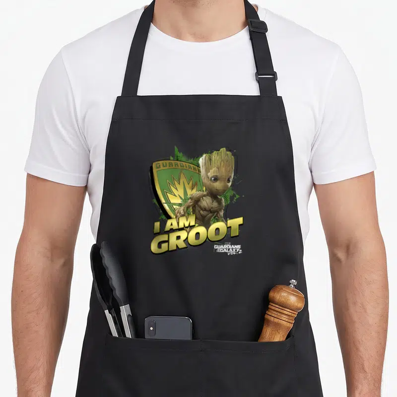 Tablier de cuisine noir avec illustration de Baby Groot tenant un bouclier vert et or.