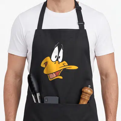 Tablier de cuisine noir avec le visage expressif de Daffy Duck aux yeux écarquillés et bec jaune ouvert.