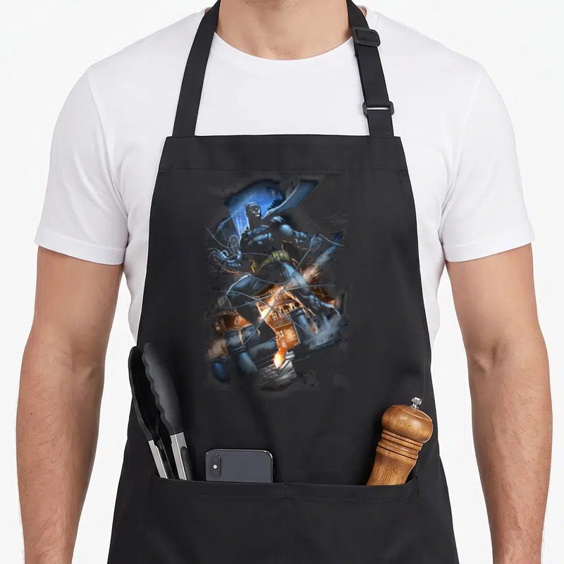 Tablier de cuisine noir avec une illustration artistique de Batman Gotham Knight en action dans un décor urbain.