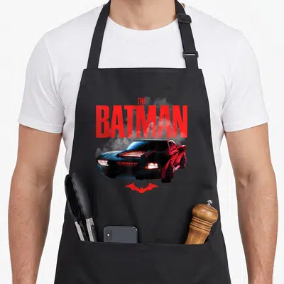 Tablier de cuisine noir avec le logo The Batman, la Batmobile et un symbole de chauve-souris rouge.