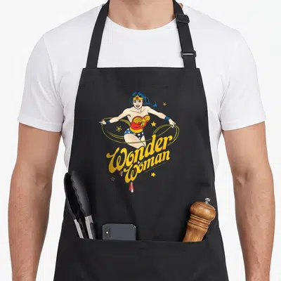 Tablier de cuisine noir avec illustration vintage de Wonder Woman tenant son lasso doré entouré d'étoiles.